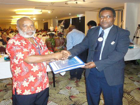 Two men shaking hands and exchanging a certificate