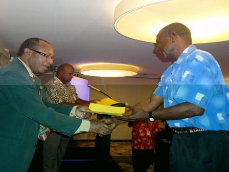 Two men shaking hands and exchanging a certificate